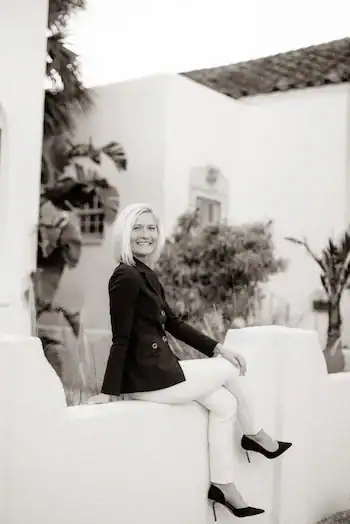 Woman on a ledge smiling at camera in a suit 