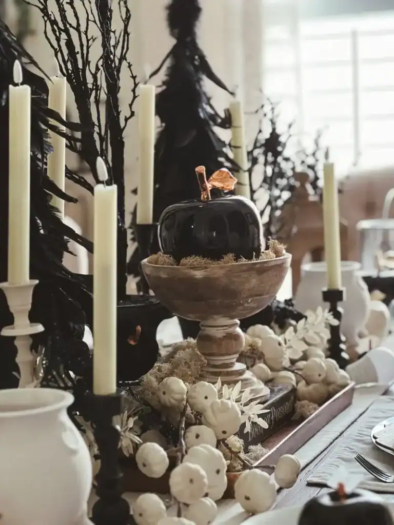 Halloween black and white tablescape with a black "poisoned" apple on a pedestal with various accents around