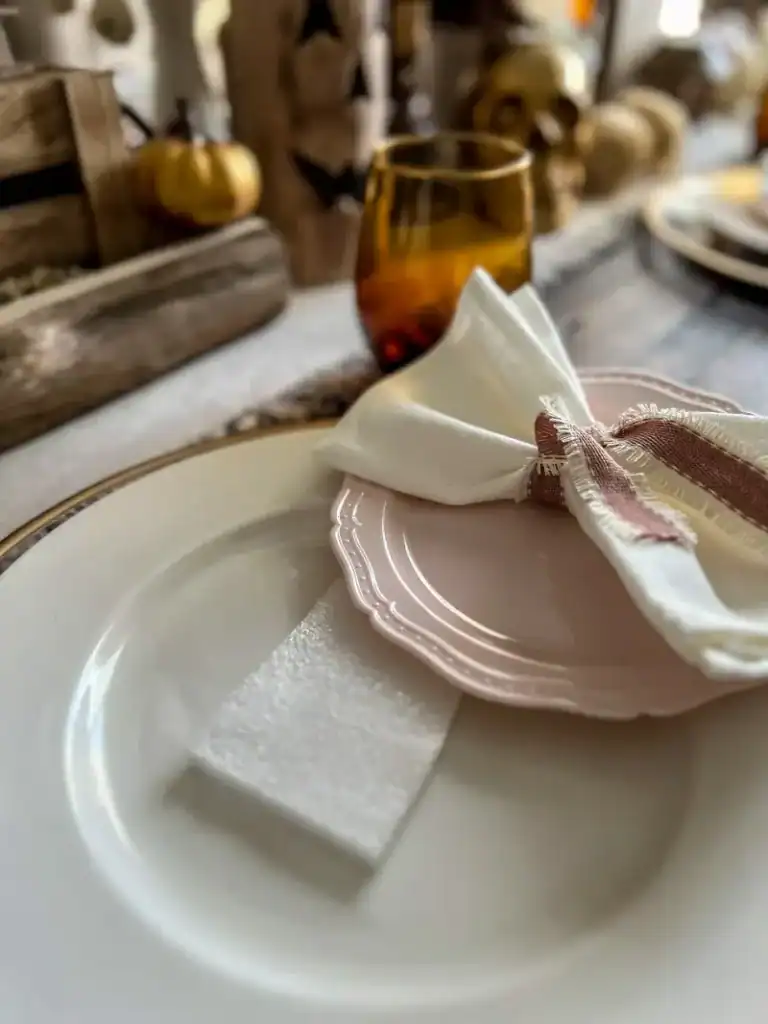 A piece of foam underneath a plastic pink plate on a topped with a white napkin with pink ribbon