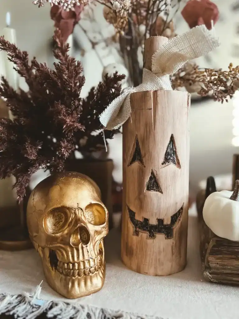 A close up of a gold skull and a carved wooden jack o lantern on a table