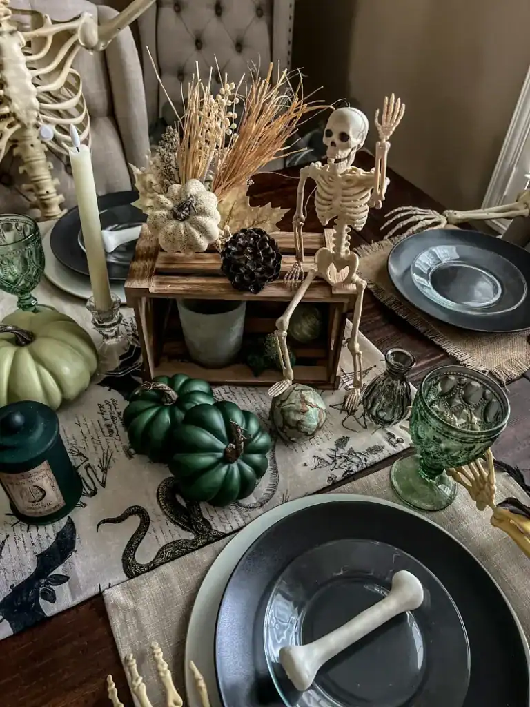 A crate that has a waving skeleton, and greenery on it with various decor items displayed like green pumpkins around it