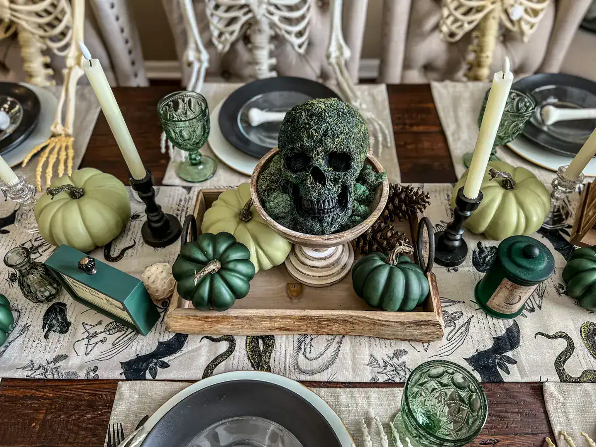 A skull covered in green moss on a pedestal for a green Halloween tablescape decor