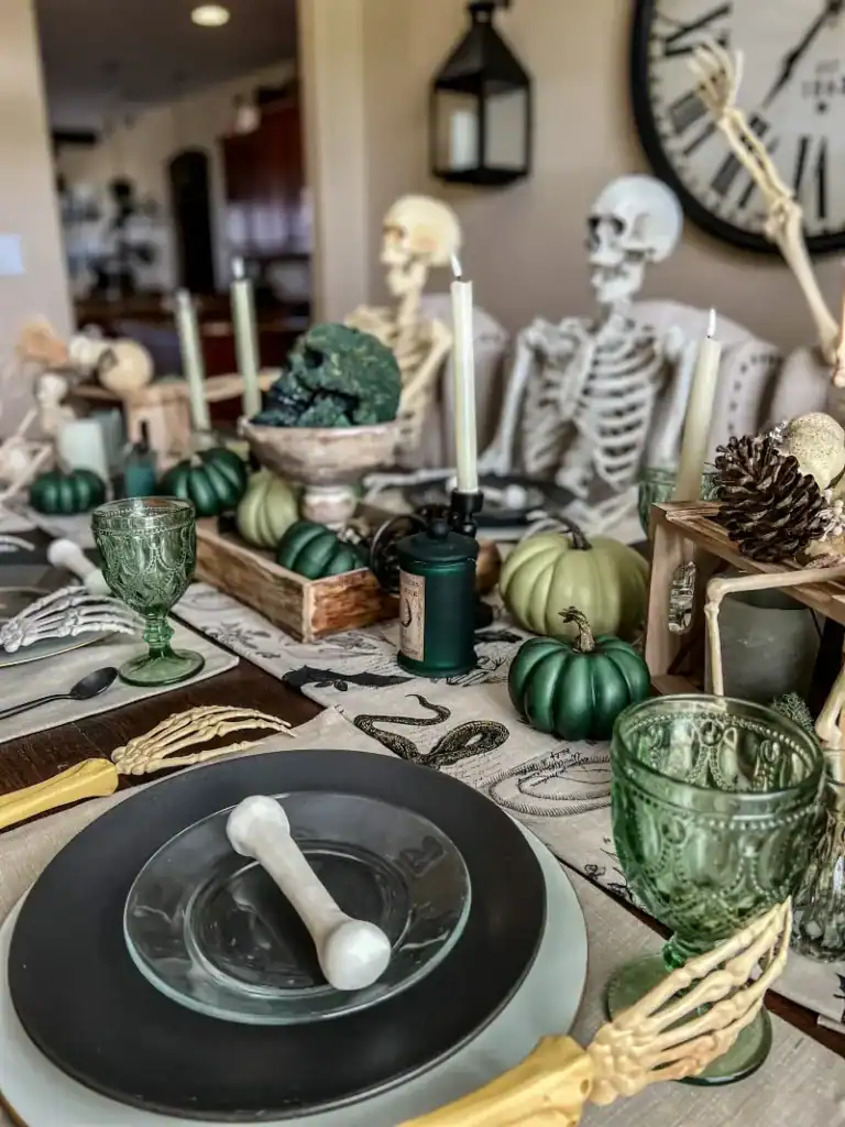 A green themed Halloween tablescape with skeletons and a black plate with a bone on it for a placesetting 