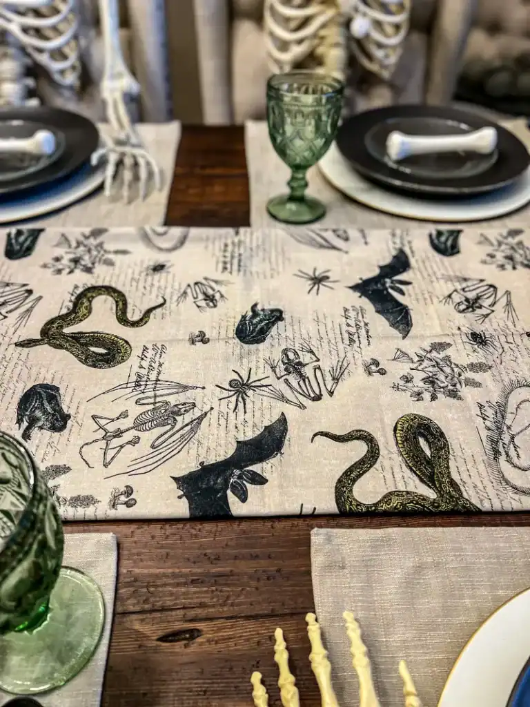 Fabric tablerunner in a Halloween theme with bats, frogs and snakes on it