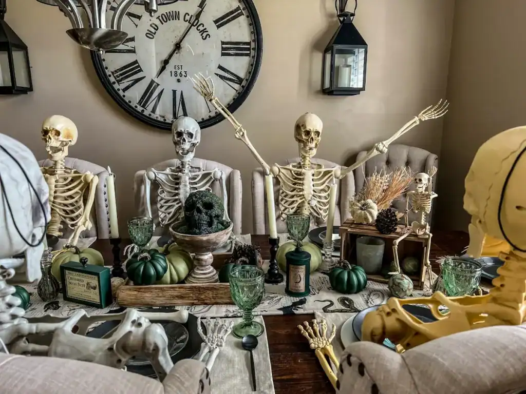 Skeletons sitting at a table decorated for halloween 