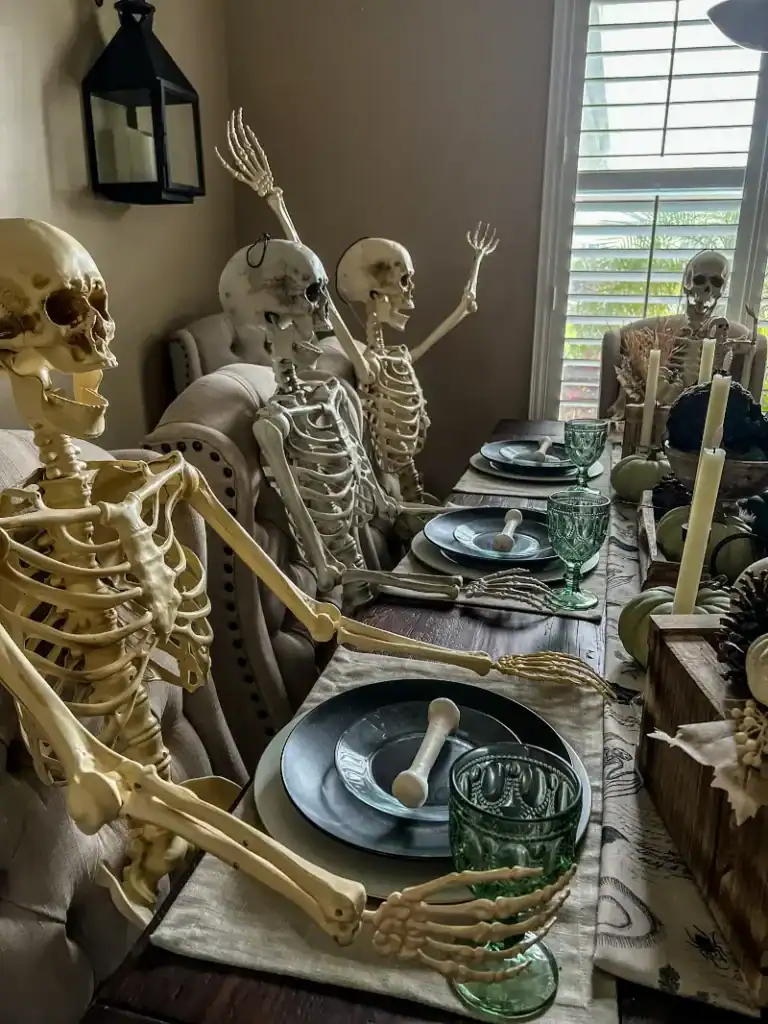 4 skeletons sitting at a dining room table with black plates in front of them 