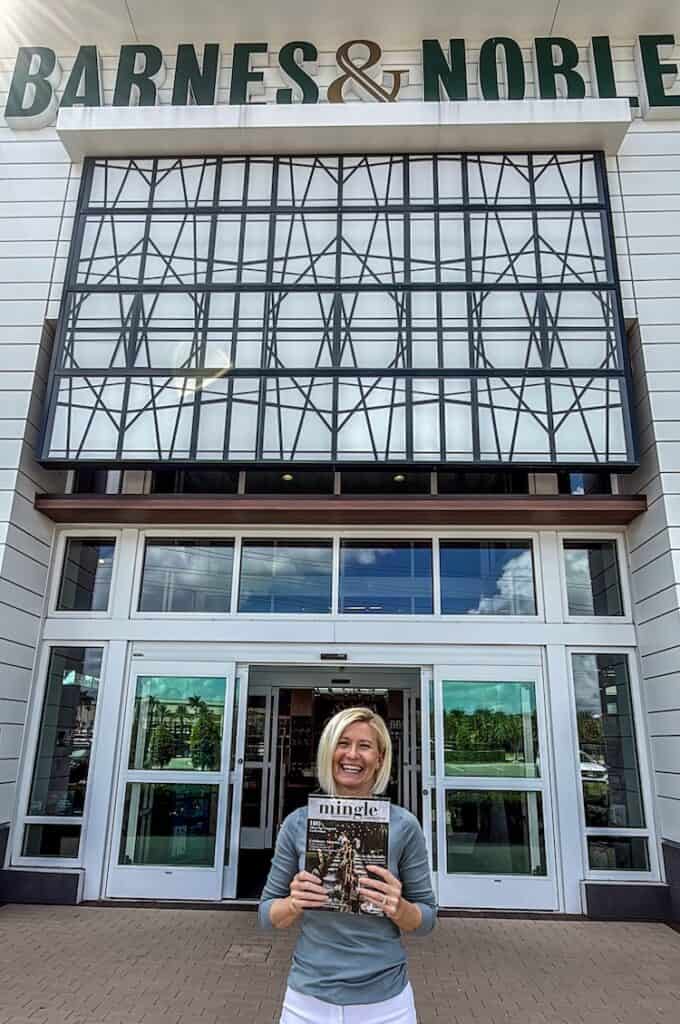 Happy woman holding a book in front of the Barnes & Noble store