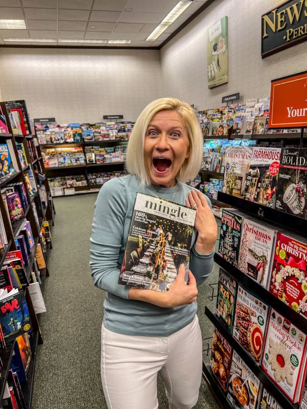 Woman excitedly holding Mingle Magazine in bookstore aisle.
