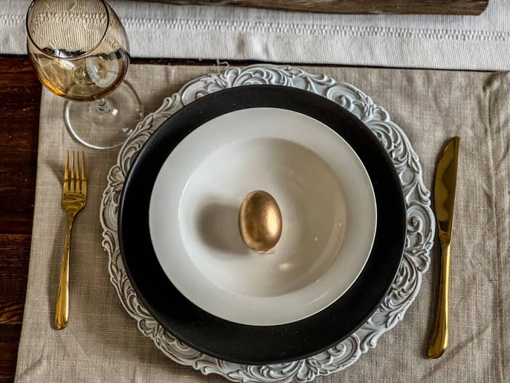 Elegant Easter table setting with a white bowl and gold egg inside