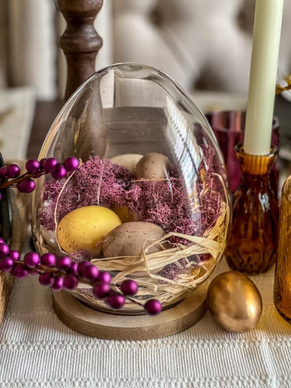 Easter dome centerpiece with purple beads, eggs, and spring decor on a festive table.