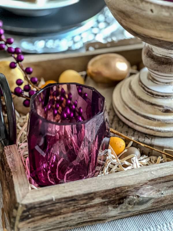 Elegant purple and yellow Easter table centerpiece with purple glassware and decorative elements.
