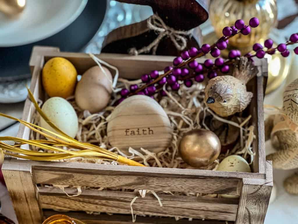 Elegant Easter table setting with a crate full of purple and yellow accents for spring celebrations and an egg that says faith inside.